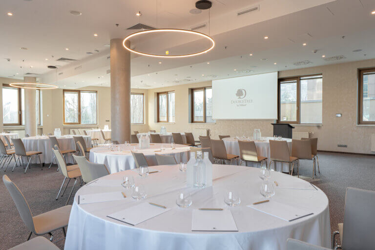 Konferenčná miestnosť hotela DoubleTree by Hilton s okrúhlymi prestretými stolmi