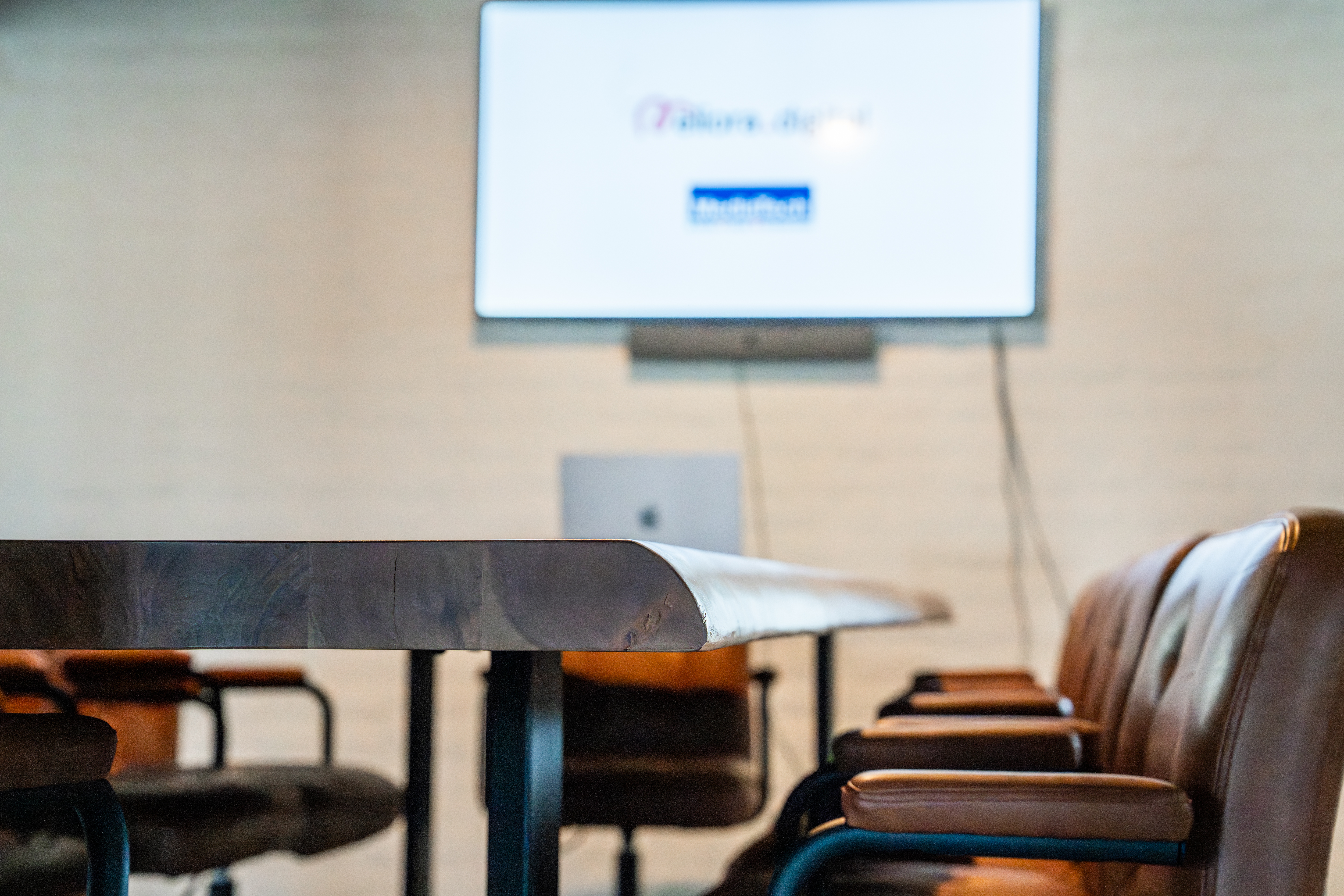 Meeting room with leather chairs and a display with a Neat device ready for BYOD connection