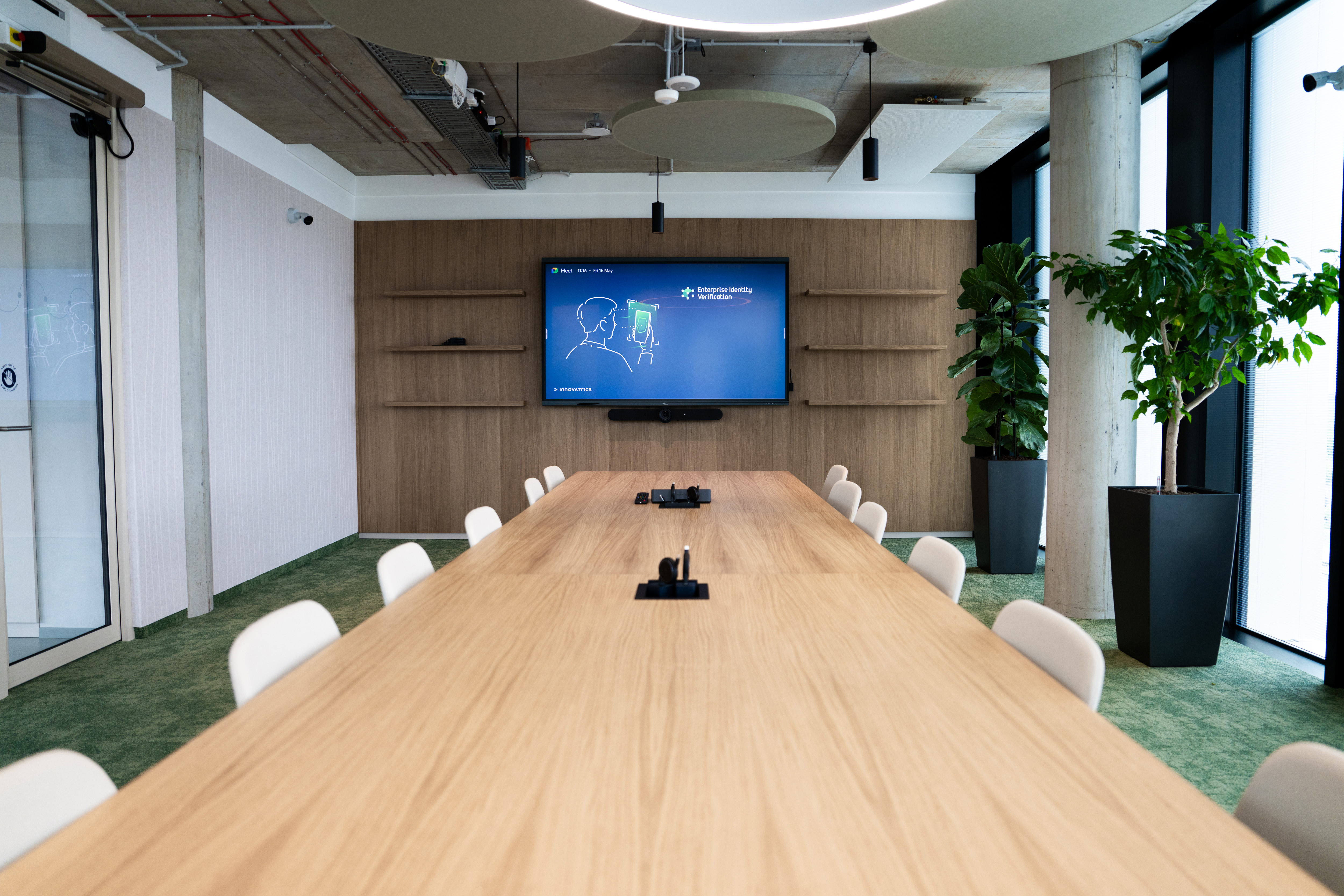 referencia_zasadacia_miestnost Long meeting room with a wooden table, white chairs and a display on a wooden wall